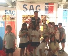 Foto funcionario SAG en stand con niños que recibieron libros y llaveros del Servicio